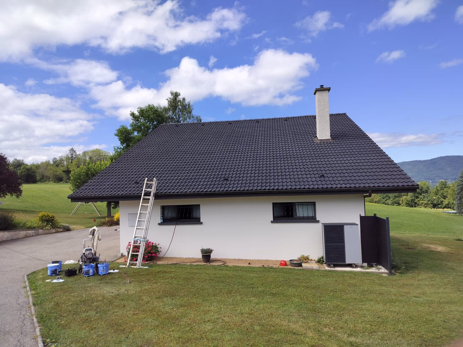 Maison en Creuse dont la toiture vient d’être nettoyée, échelle et matériel de chantier au pied du mur