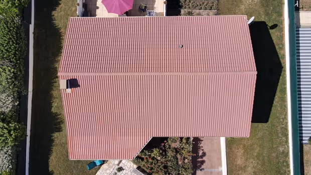 Toiture en tuiles délavées vue du ciel, teinte passée et surface irrégulière